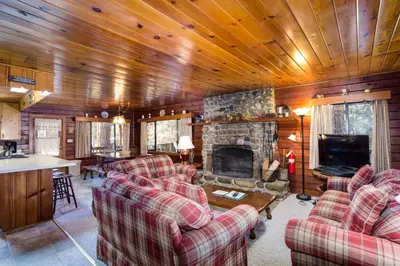 a living room with two couches and a stone fireplace at 55 Deer Creek in Wawona