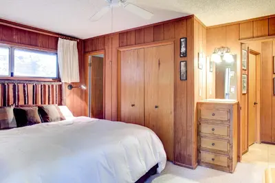 a bedroom with a white bed and a wooden wall at 12B Star Gazers in Wawona