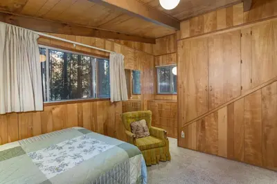 a bedroom with a bed and a chair and a window at 3A Cutters Edge in Wawona