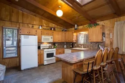 a kitchen with a white refrigerator and wooden cabinets at 3A Cutters Edge in Wawona