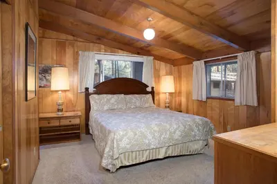 a bedroom with a bed and two windows at 3A Cutters Edge in Wawona