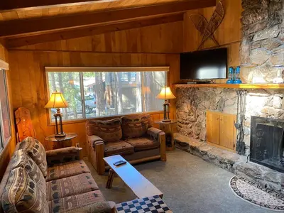 a living room with a couch and a stone fireplace at 3A Cutters Edge in Wawona
