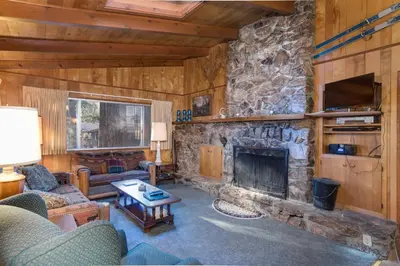 a living room with a stone fireplace in a cabin at 3A Cutters Edge in Wawona