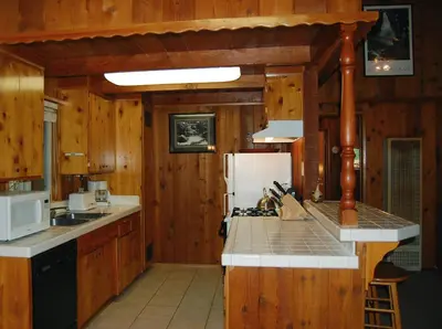a kitchen with wooden walls and a white refrigerator at 30A Dunnings Retreat in Wawona