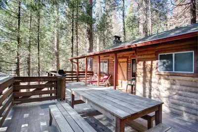 a wooden deck of a cabin in the woods at 70 Simmons Den in Wawona