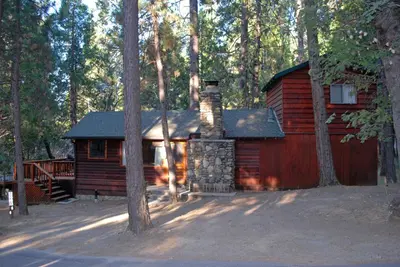 a log cabin in the middle of a forest at 6 Squirrels Nest in Wawona