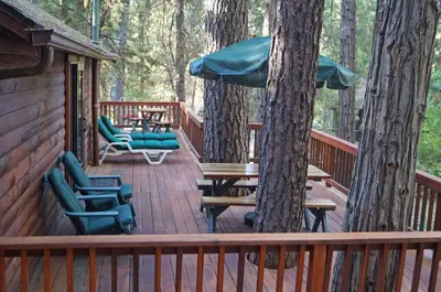a wooden deck with chairs and tables and trees at 6 Squirrels Nest in Wawona