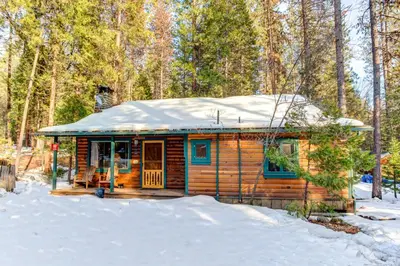 a log cabin in the snow with a snow covered roof at 59 Hansen Cabin in North Wawona