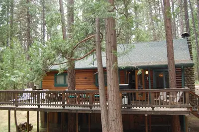 a log cabin with a deck in the woods at 59 Hansen Cabin in North Wawona