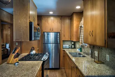 a kitchen with wooden cabinets and a stainless steel refrigerator at 23 Arnetts Cabin in North Wawona