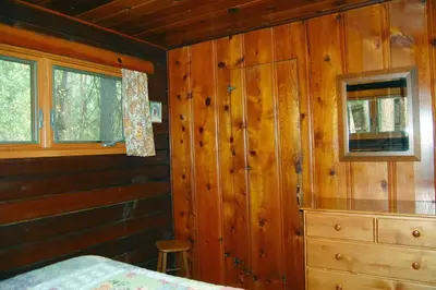 a bedroom with wooden walls and a bed and a window at 8 Nugents Nest in North Wawona