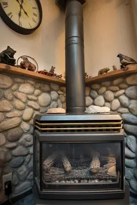 a stone fireplace with a clock on a wall at 42R Rosenberg's Creekside Cabin in Wawona