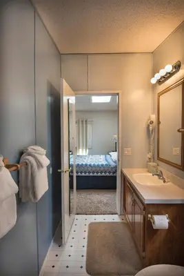 a bathroom with a sink and a bedroom with a bed at 42R Rosenberg's Creekside Cabin in Wawona