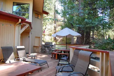 a patio with tables and chairs and an umbrella at 18A Pohono Pines in Wawona