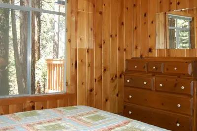 a bedroom with a bed and a dresser and a window at 9S Pine Cabin in South Wawona