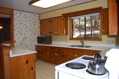 a kitchen with wooden cabinets and a white stove top oven at 9S Pine Cabin in South Wawona