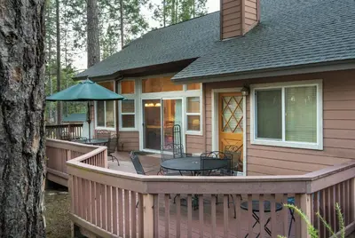 a house with a deck with a table and chairs at 2A The Terry Cabin in North Wawona