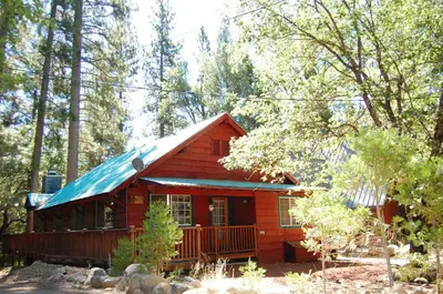 a red cabin with a blue roof in the woods at 10N Black Oak Lodge in Wawona