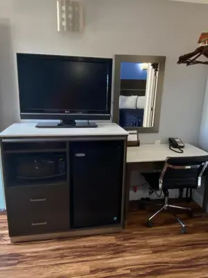 a desk with a television and a desk with a computer at Oasis Inn Sacramento- Elk Grove in Sacramento