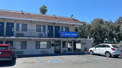 a building with a car parked in a parking lot at Motel 6 Modesto, CA in Modesto