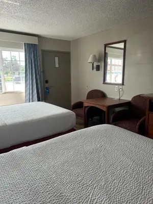 a hotel room with two beds and a desk and a window at Days Inn by Wyndham Turlock in Turlock