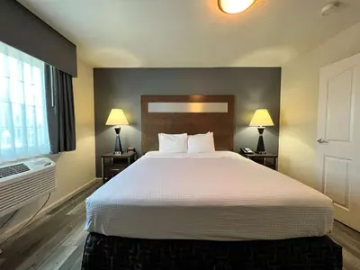 a bedroom with a large bed with white sheets and two lamps at Best Western Americana in Dinuba