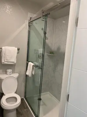 a bathroom with a toilet and a glass shower at Elmwood Motel in Auburn