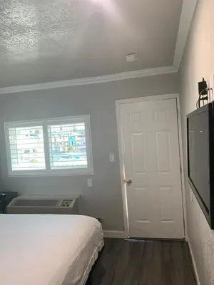 a bedroom with a bed and a tv and a door at Elmwood Motel in Auburn