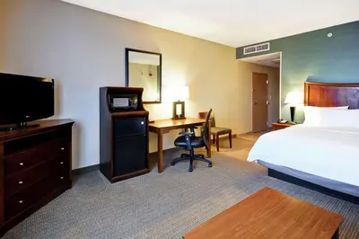a hotel room with a bed and a desk with a television at Hampton Inn & Suites Folsom in Folsom