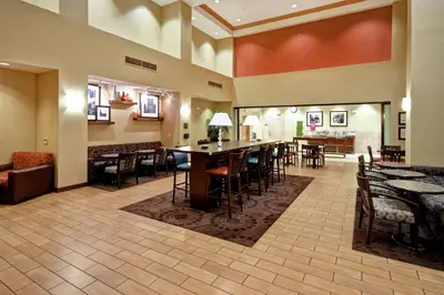 a restaurant with tables and chairs and a bar at Hampton Inn & Suites Folsom in Folsom