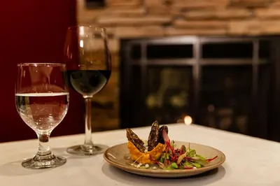 a plate of food and a glass of wine on a table at Tenaya at Yosemite in Fish Camp