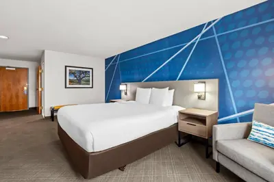 a hotel room with a large bed and a chair at Comfort Inn South San Jose - Morgan Hill in Morgan Hill