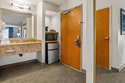 a bathroom with a sink and a mirror and a door at Comfort Inn South San Jose - Morgan Hill in Morgan Hill
