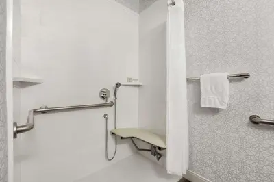a bathroom with a shower with a chair in it at Hampton Inn Sacramento/Rancho Cordova in Rancho Cordova
