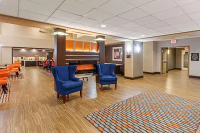 a waiting room with blue chairs and a piano at Hampton Inn and Suites Merced in Merced