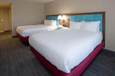 a hotel room with two beds with white sheets at Hampton Inn Visalia in Visalia