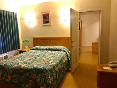 a hotel room with a bed and a desk and a door at Sunrise Inn in Turlock