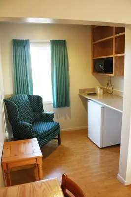 a living room with a chair and a kitchen at Sunrise Inn in Turlock