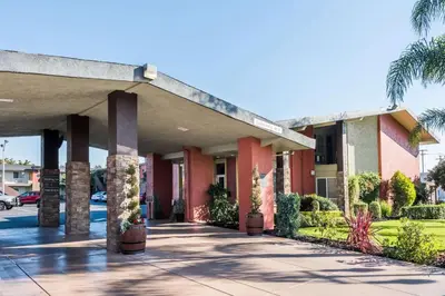 a large building with palm trees and a sidewalk at Days Inn & Suites by Wyndham Lodi in Lodi