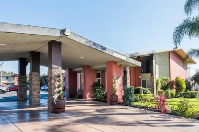 a large building with palm trees and a sidewalk at Days Inn & Suites by Wyndham Lodi in Lodi