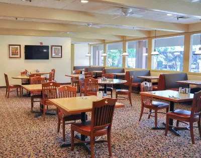 a restaurant with tables and chairs and a bar at Piccadilly Inn Airport in Fresno