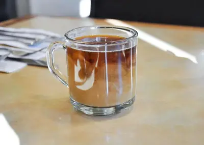 a glass mug of coffee sitting on a table at Piccadilly Inn Airport in Fresno