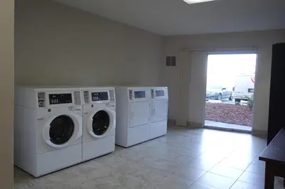 a laundry room with three washing machines and a window at Ramada by Wyndham Sacramento in Sacramento