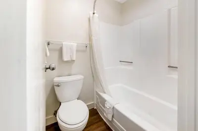 a white bathroom with a toilet and a bath tub at Rodeway Inn at Nevada State Capitol in Carson City