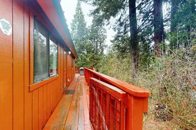 an orange house with a wooden walkway in the woods at Deaver's Place in Shaver Lake