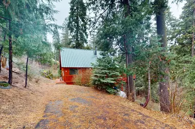 a red cabin in the middle of a forest at Deaver's Place in Shaver Lake