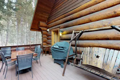 a deck with a table and chairs on a log cabin at Loggers Landing in Lakeshore