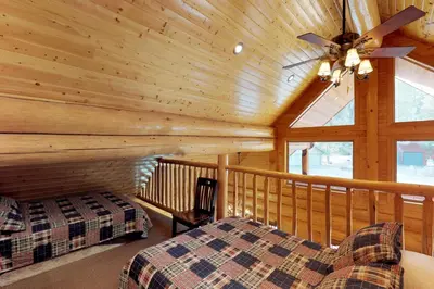 a log cabin with a bed and a ceiling fan at Loggers Landing in Lakeshore