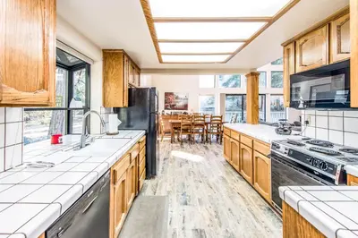 a kitchen with wooden cabinets and a dining room at Paw's Cabin in Shaver Lake