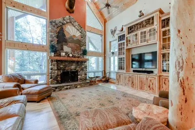 a living room with a stone fireplace and a tv at Pinnacle Point in Shaver Lake
